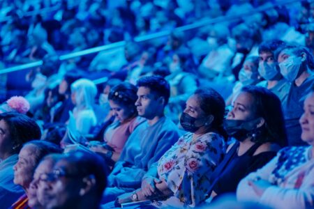 Audience members sitting in theater seats watching a live performance