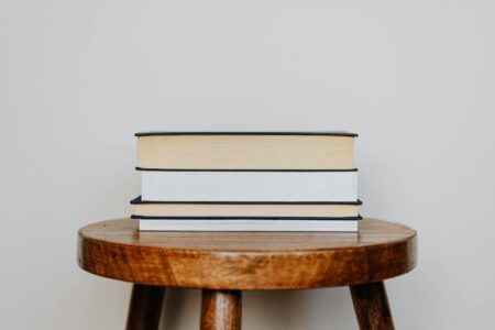 The Real Story Behind Celebrity Book Club Recommendations Going Viral Stack of books arranged on a wooden table surface