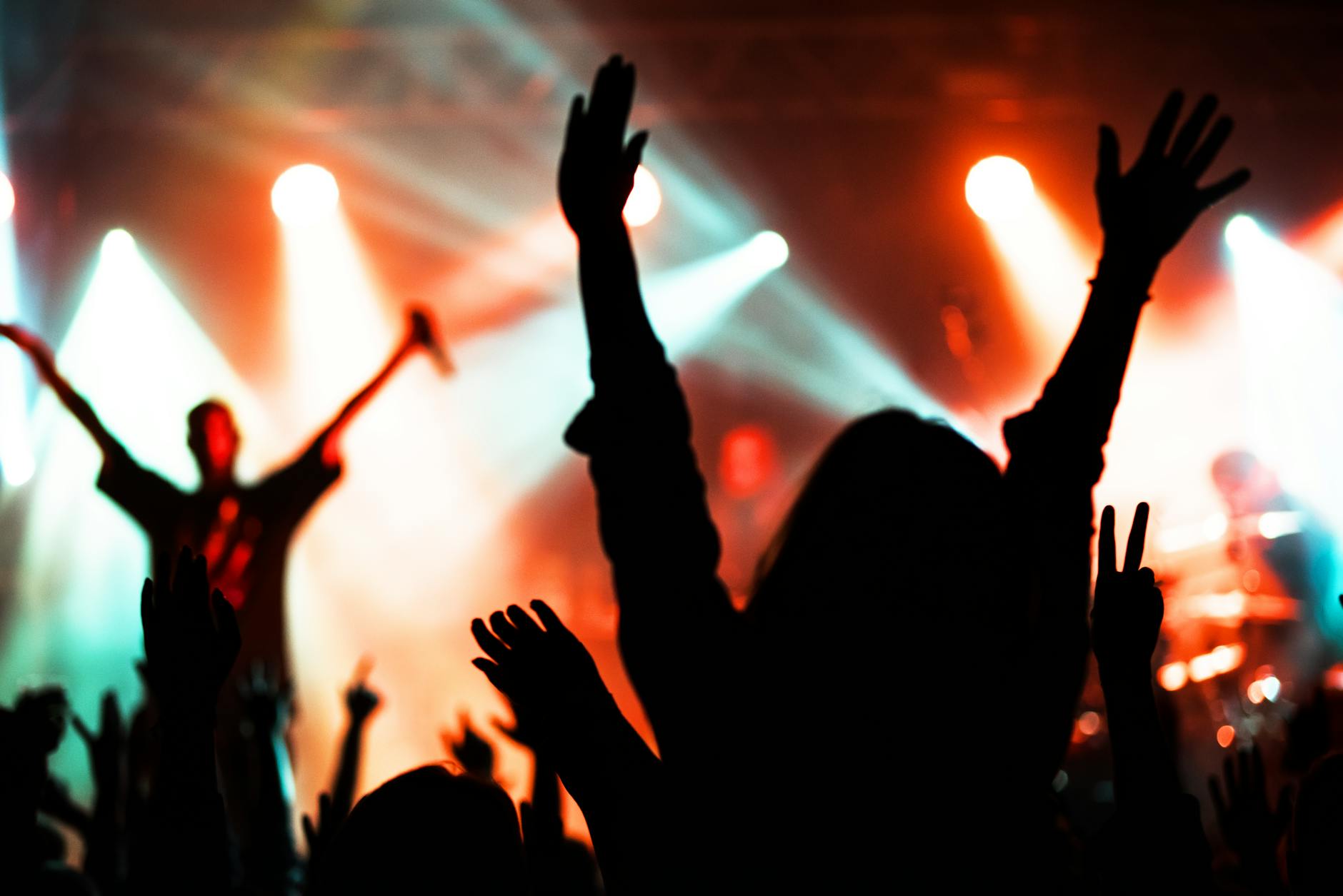 Silhouettes of concert audience with colorful stage lights creating an immersive atmosphere