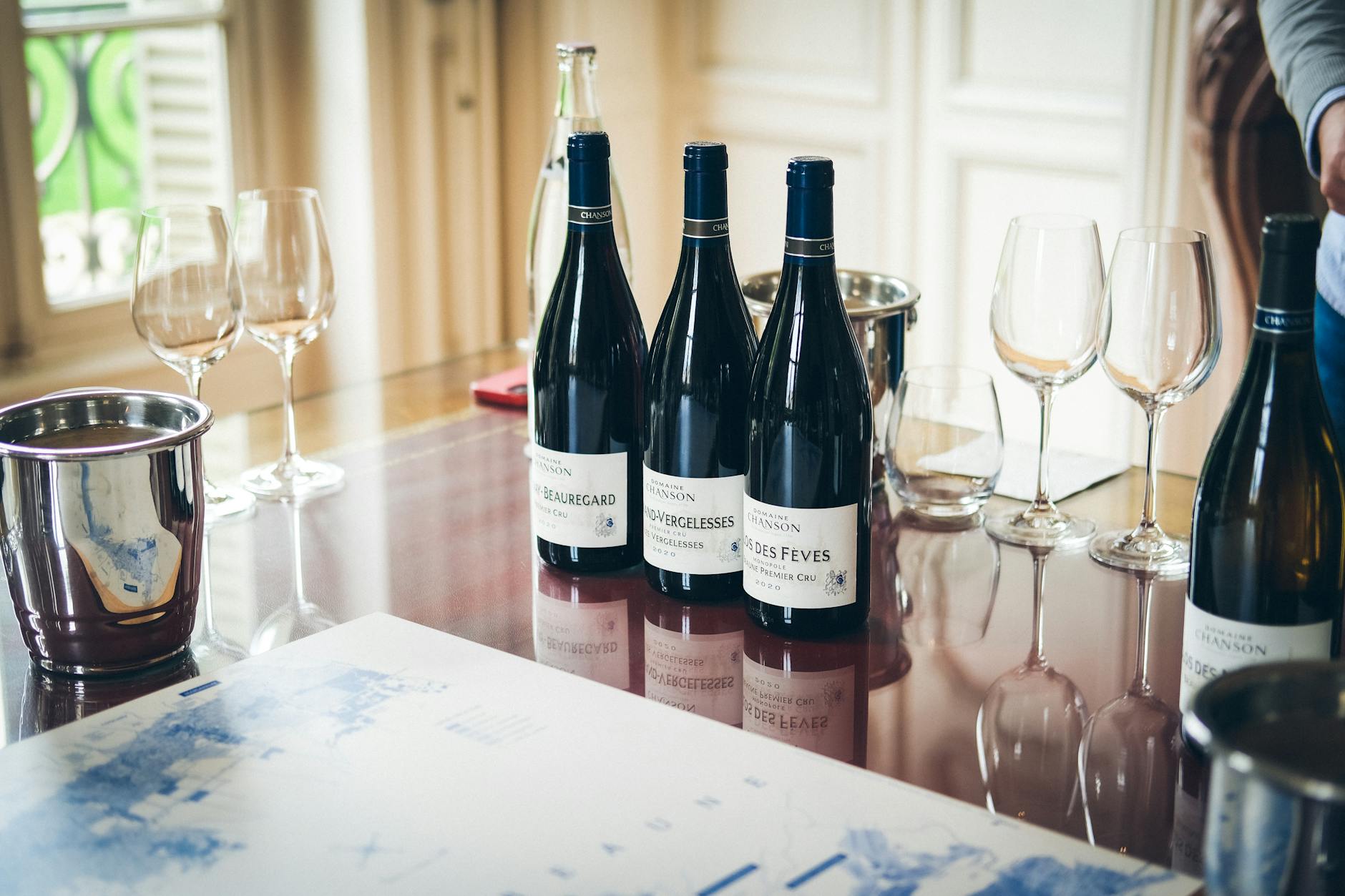 Wine bottles arranged on wooden table with glasses and casual dining setup