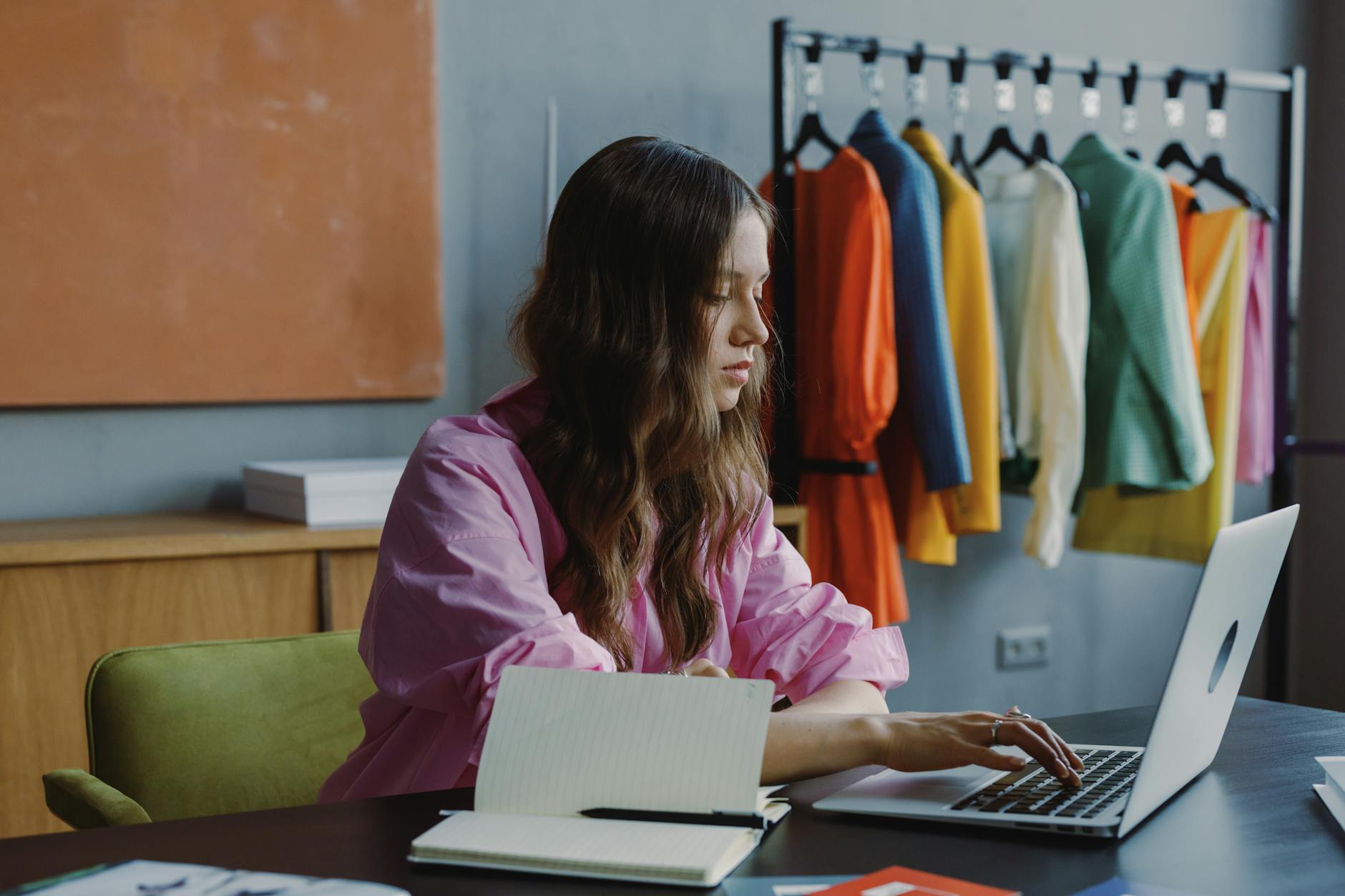 Fashion designer sketching dress designs at studio workspace