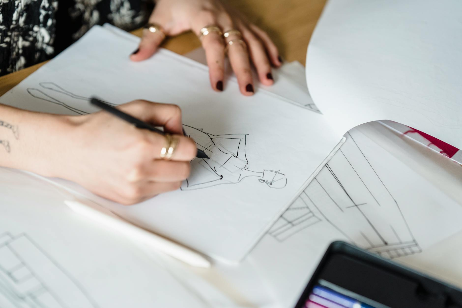 Fashion design sketches and fabric swatches on a designer's desk showing the creative process behind clothing collections