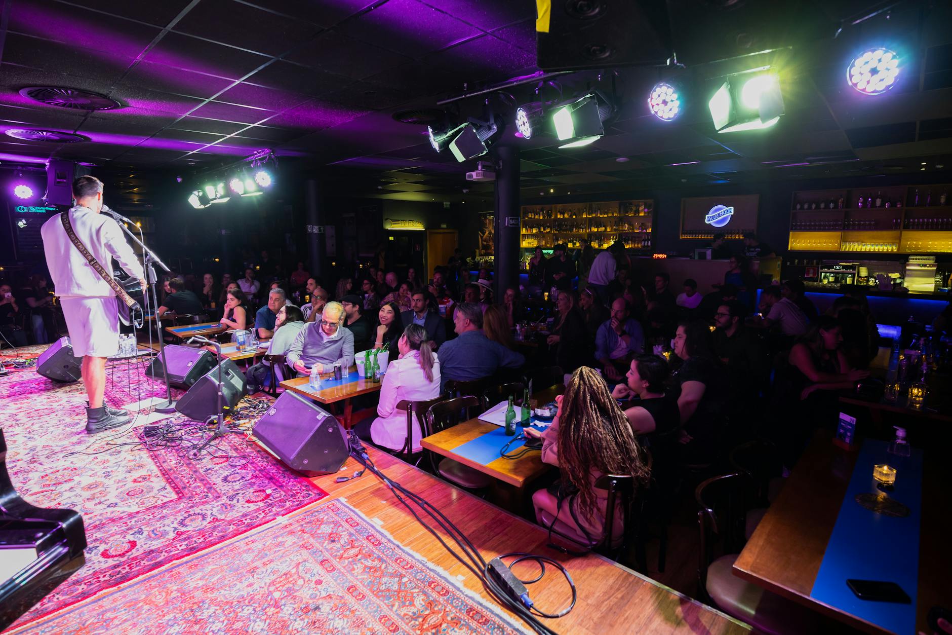Interior of a comedy club with stage, microphone, and intimate seating arrangement