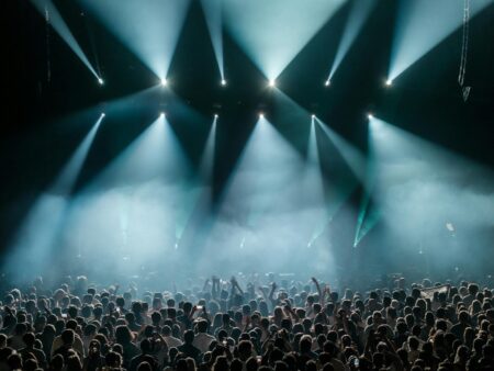 A large crowd at an indoor arena concert with colorful stage lighting