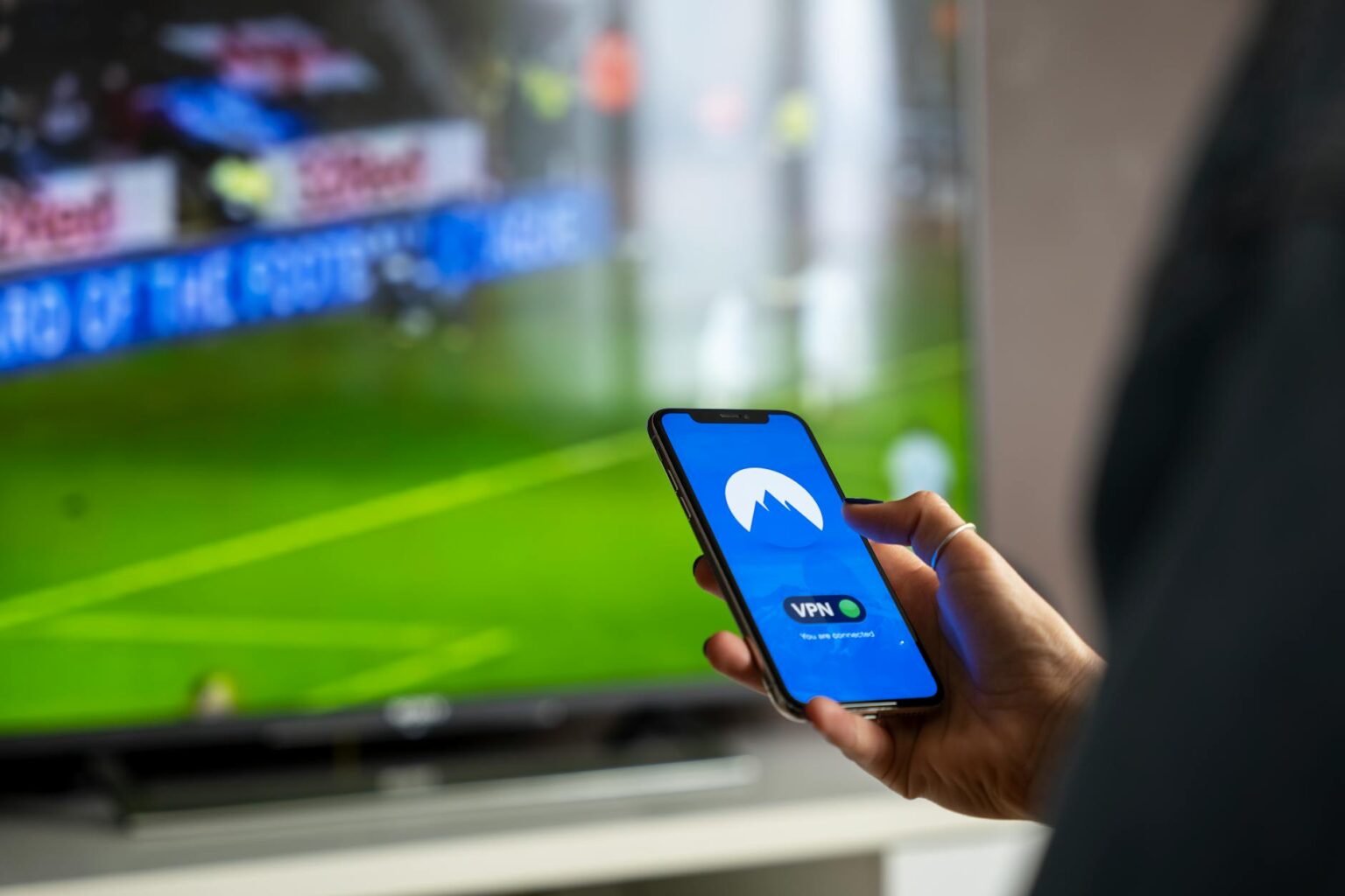 Person using TV remote to browse streaming content on television screen