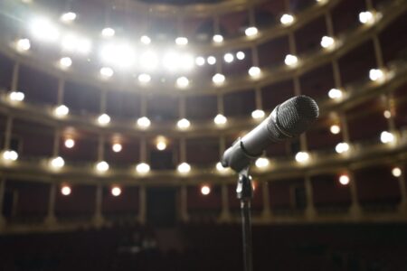 Empty theater stage lit by a single spotlight, representing performance and dramatic artistry