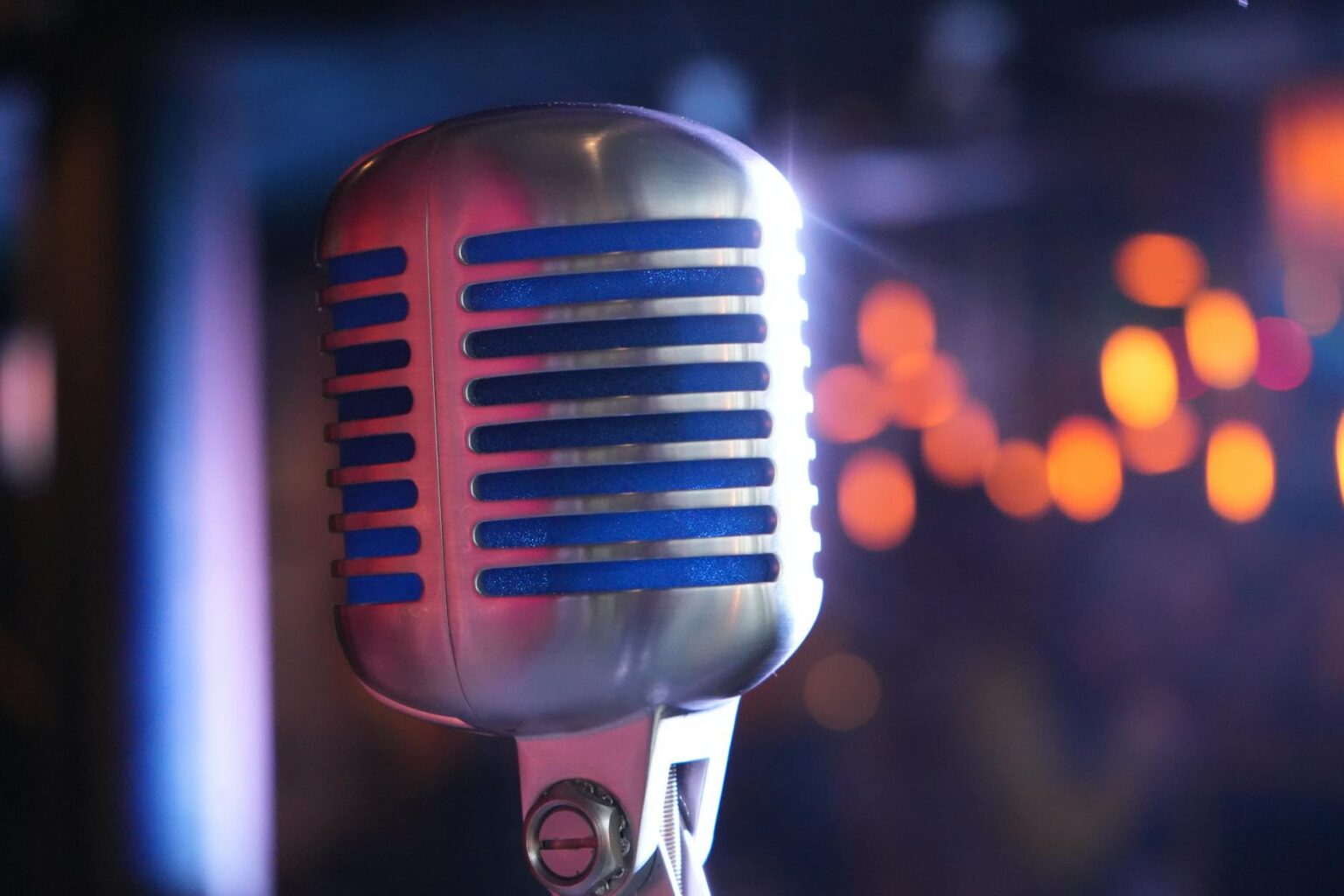 Comedy Central’s Late-Night Strategy Shift Toward Younger Stand-Up Talent Professional microphone on dimly lit comedy club stage with spotlights