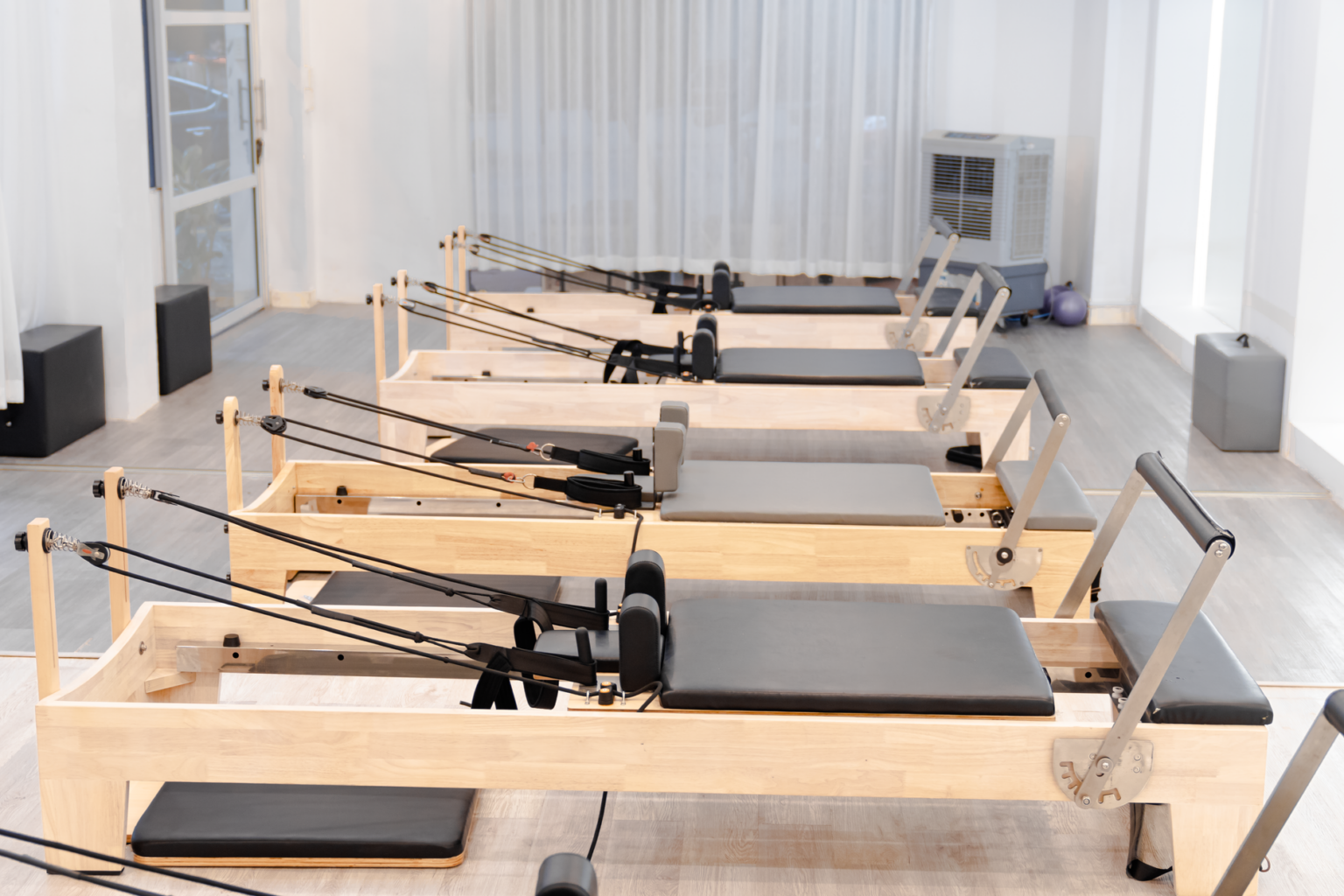 A bright reformer Pilates studio with rows of reformer machines ready for class