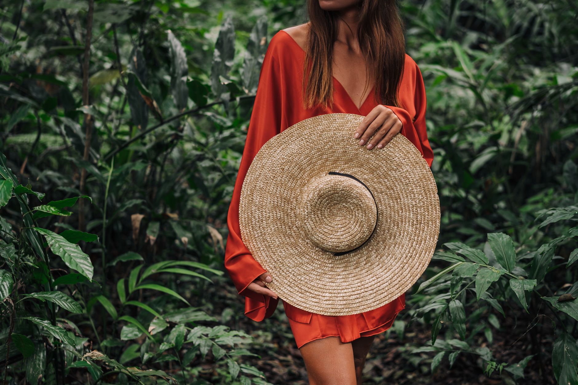 A woman wearing a dramatically wide-brimmed straw hat outdoors in natural light