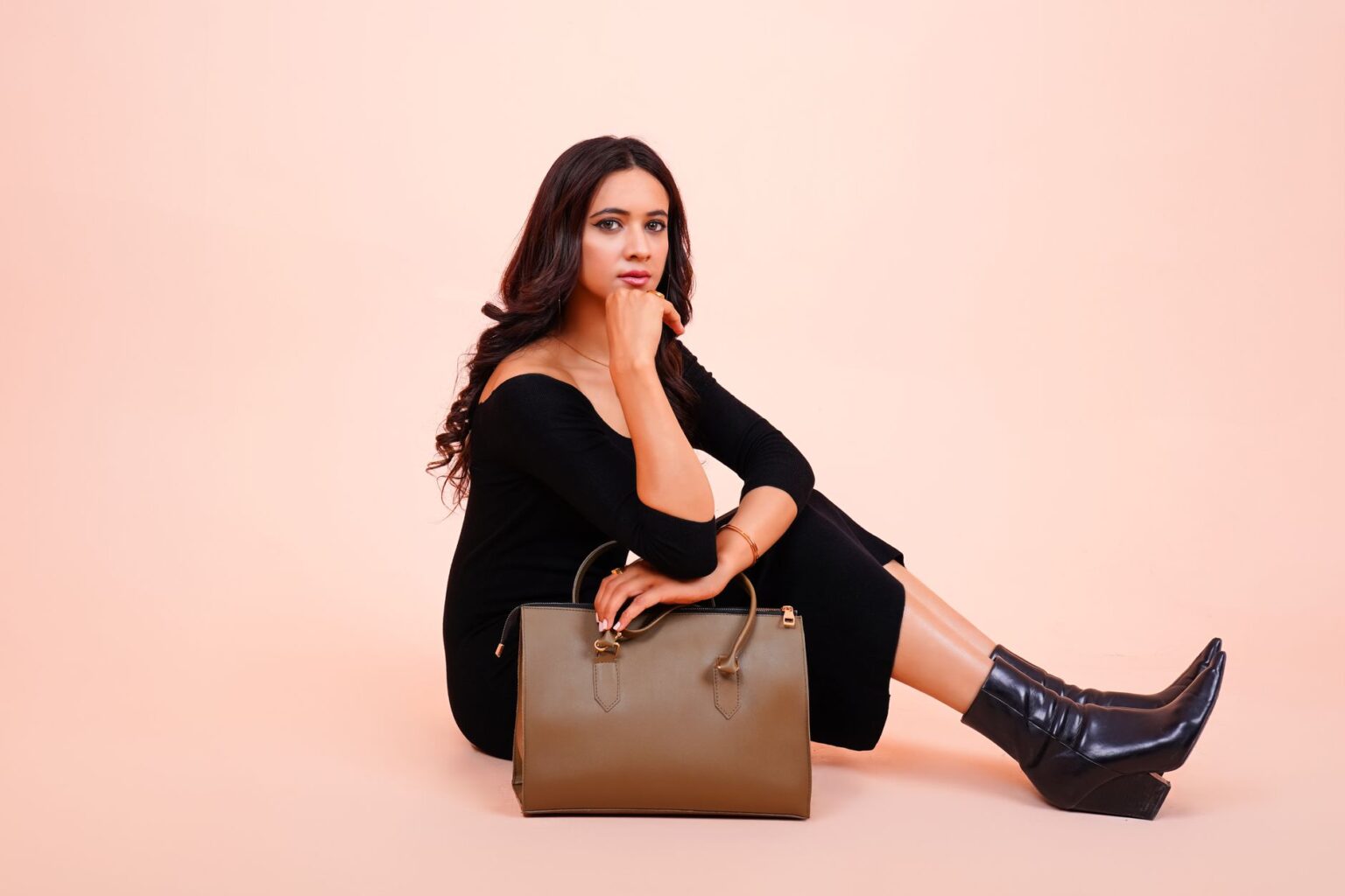 Close-up of a structured vegan leather handbag with chain detail on a neutral background
