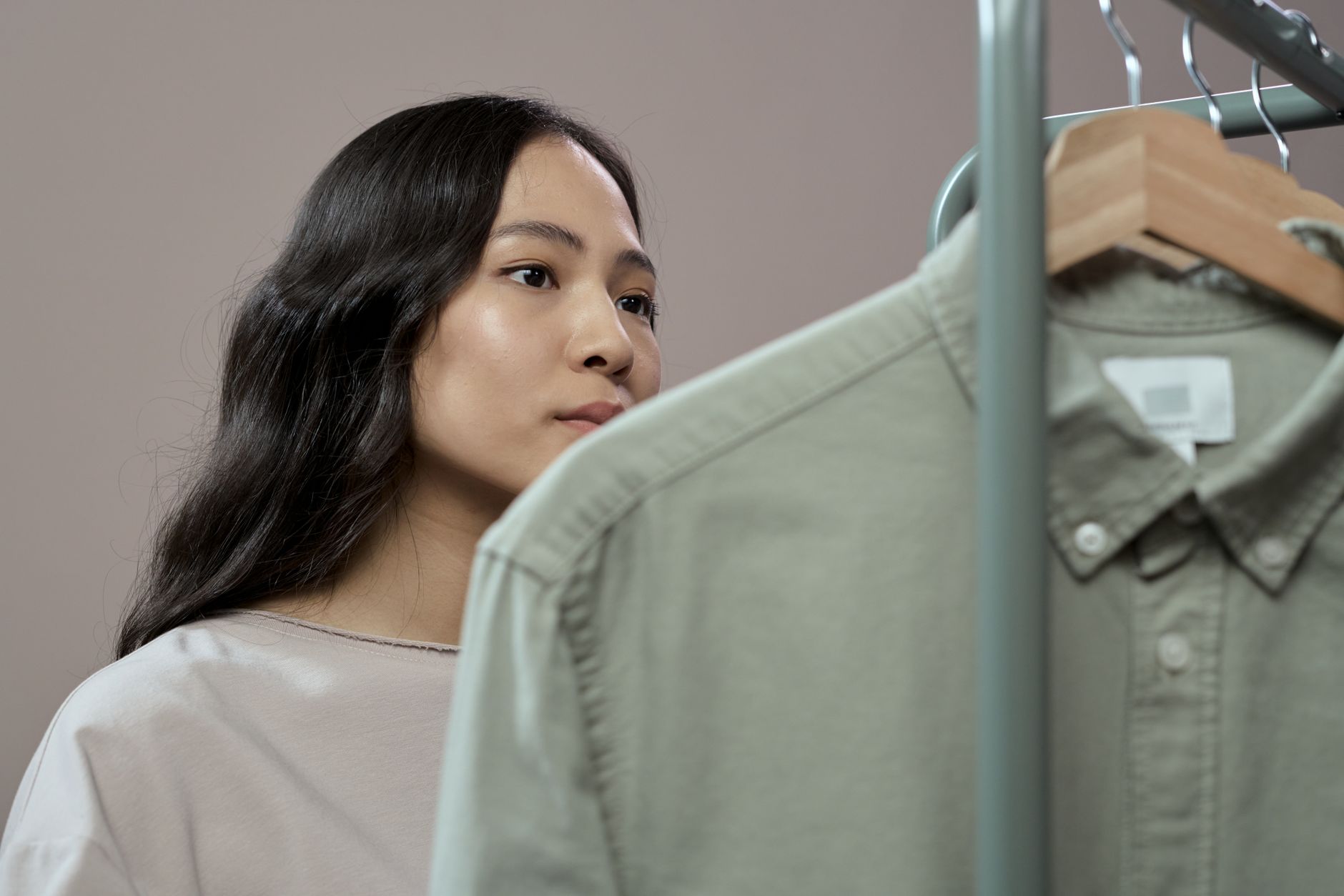A curated rack of minimal wardrobe basics in neutral colors hanging in a clean studio setting