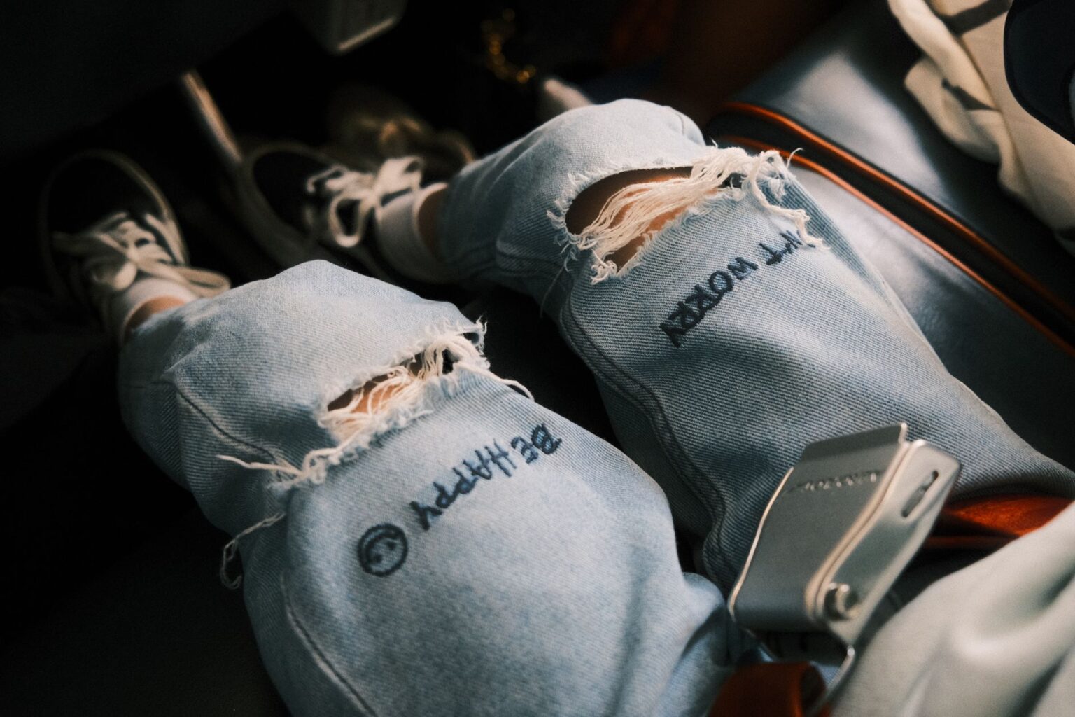 Close-up of worn distressed denim jeans with faded wash and frayed details