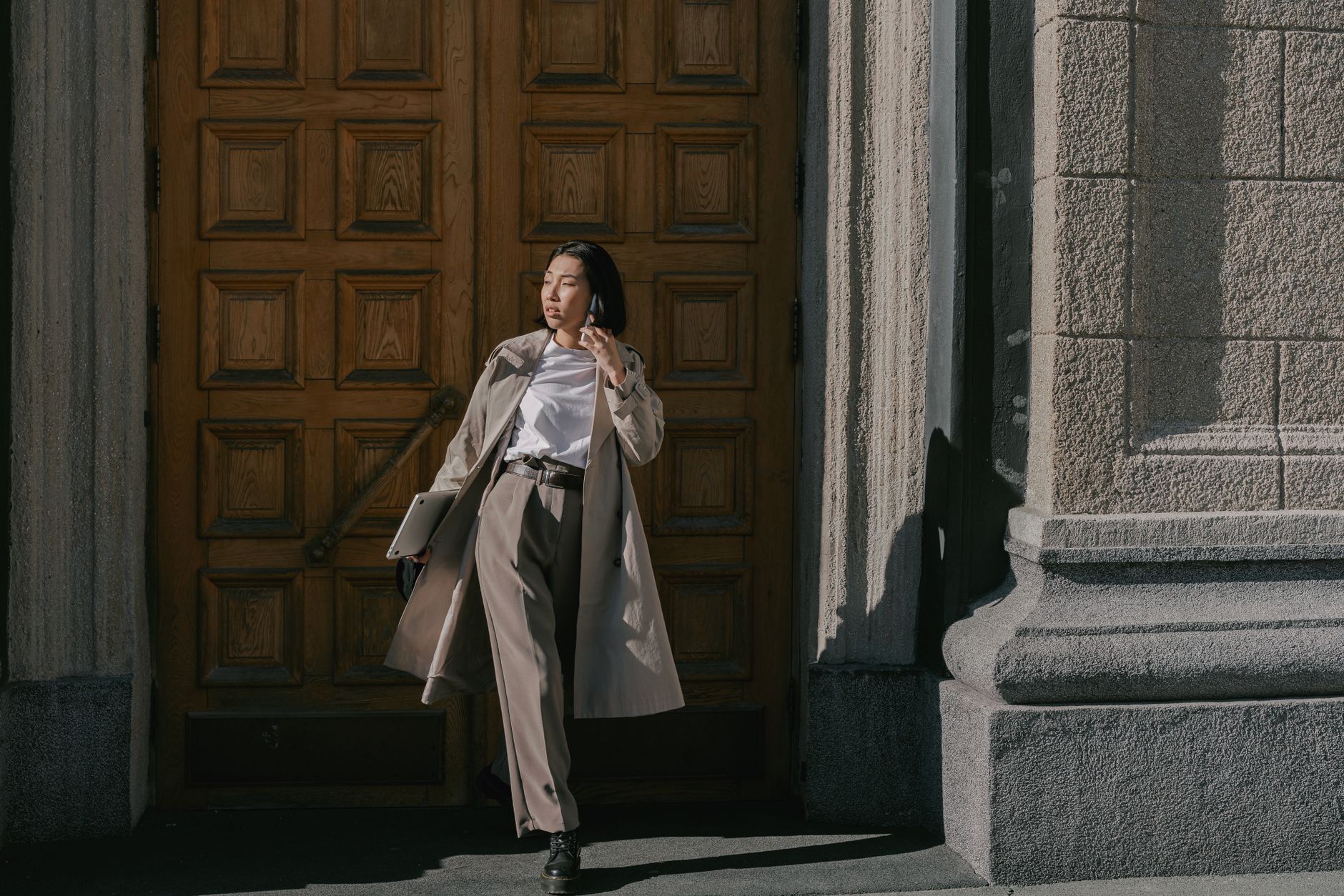 Woman wearing a structured belted trench coat on a city street