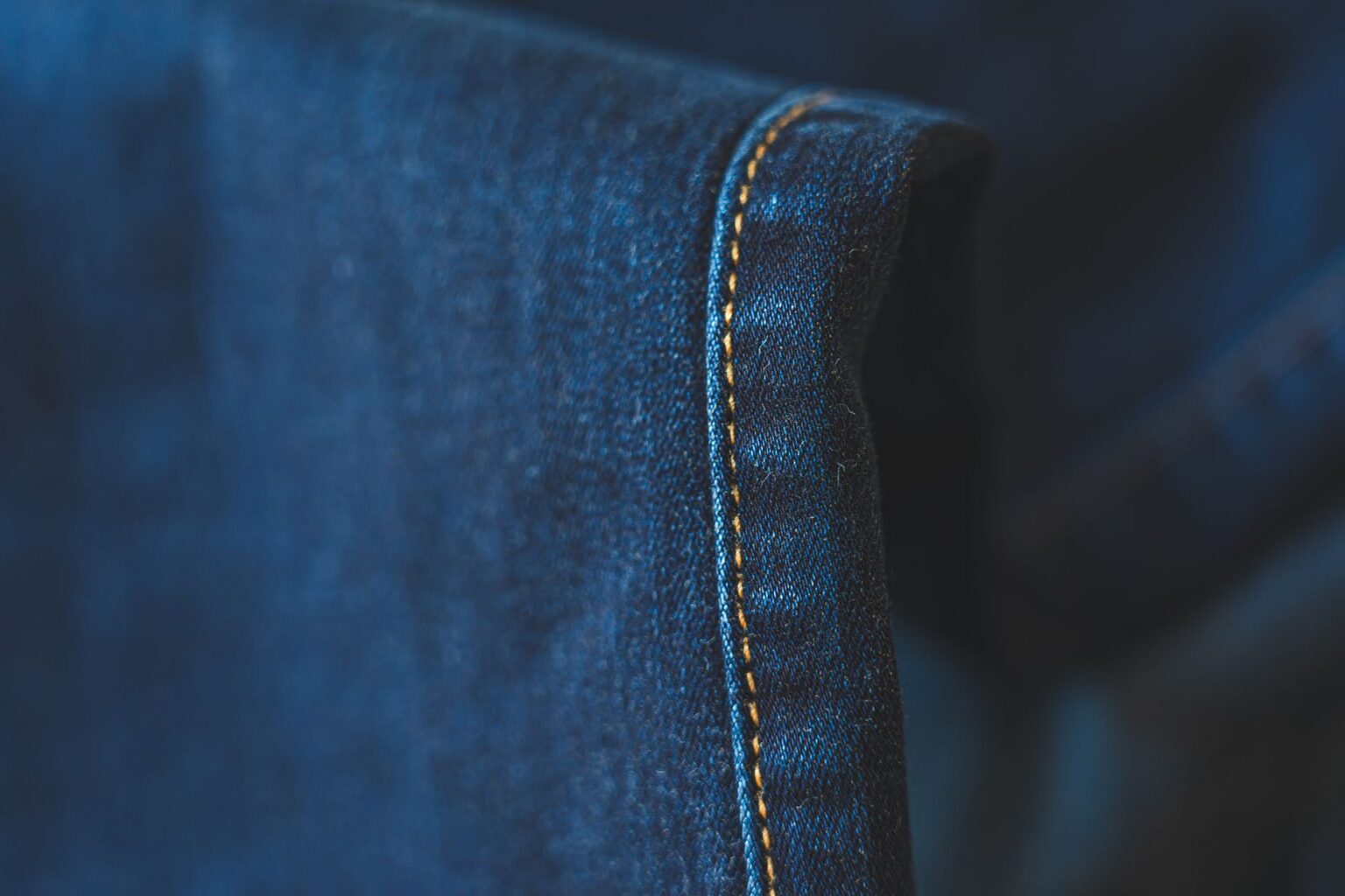 Close-up of raw hem denim jeans showing unfinished frayed edge at ankle