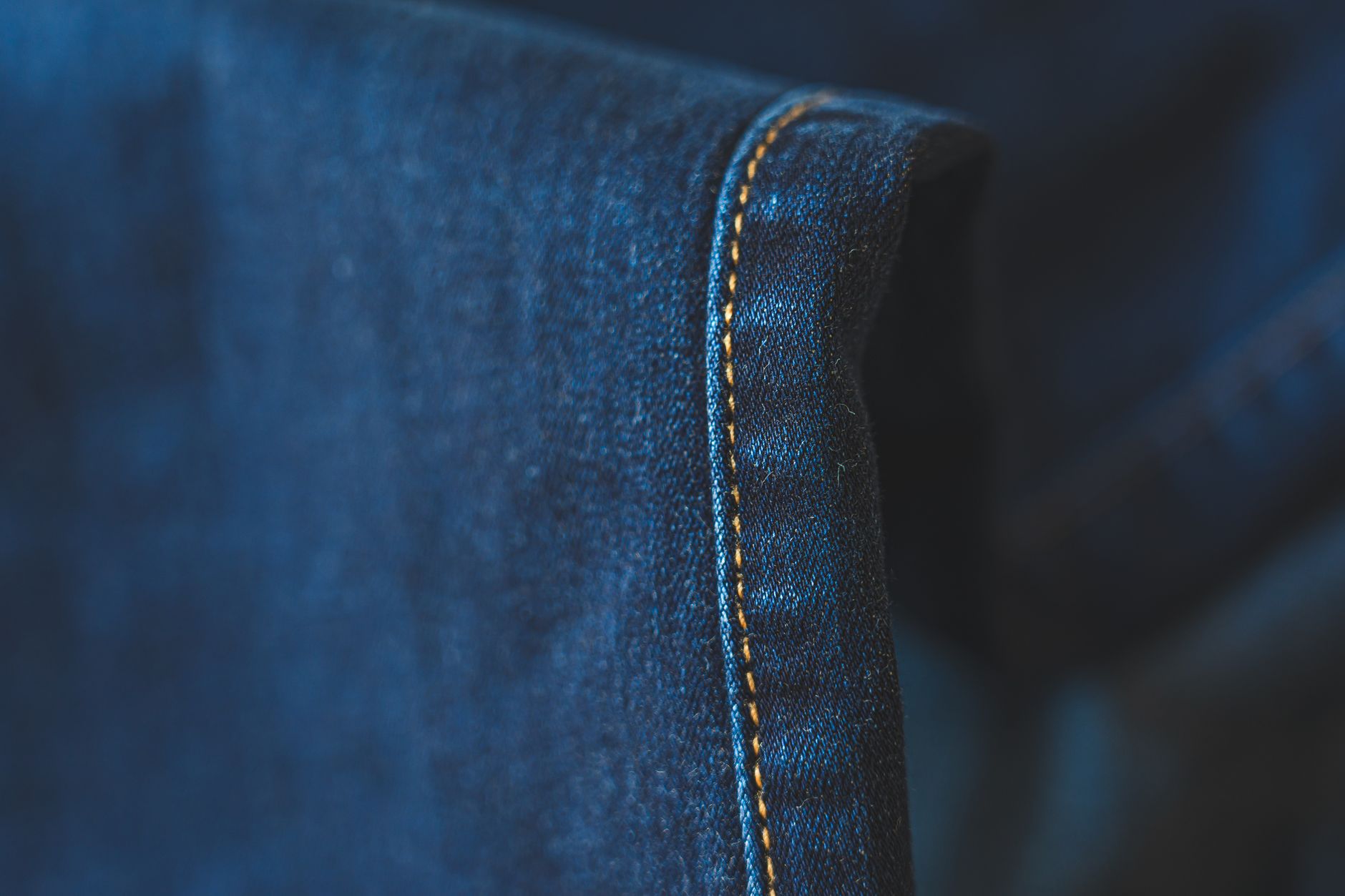 Close-up of raw hem denim jeans showing unfinished frayed edge at ankle