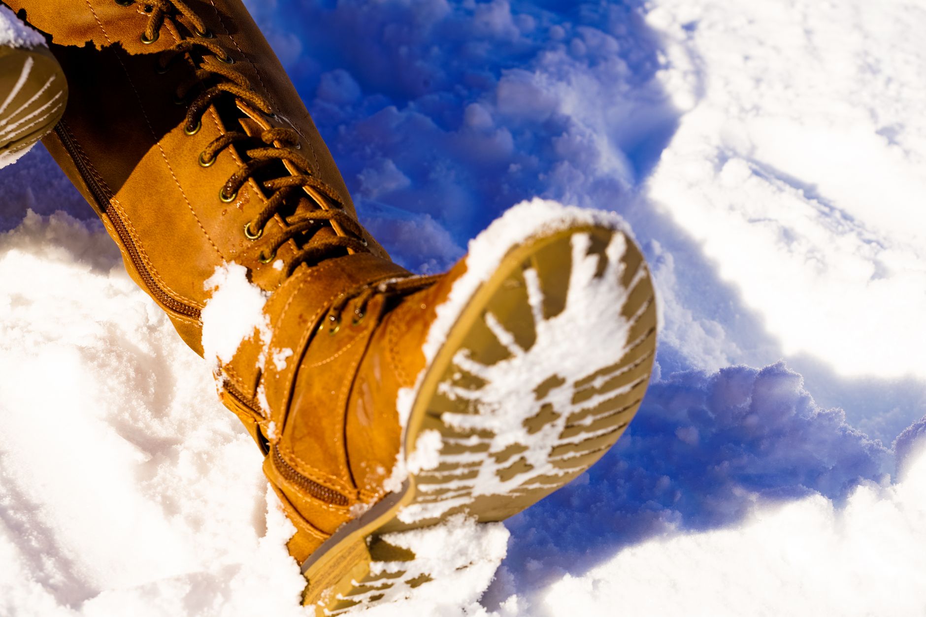 Close-up of structured leather calf-height boots on a wooden floor