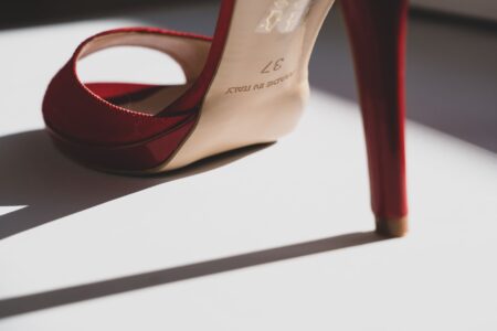 Close-up of a pair of elegant stiletto heels with gold hardware detail against a neutral background