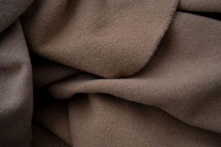 Close-up of a soft cashmere fabric in a neutral tone, showing fine texture and quality