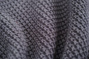 A finely knit merino wool sweater in a neutral cream tone folded neatly on a surface