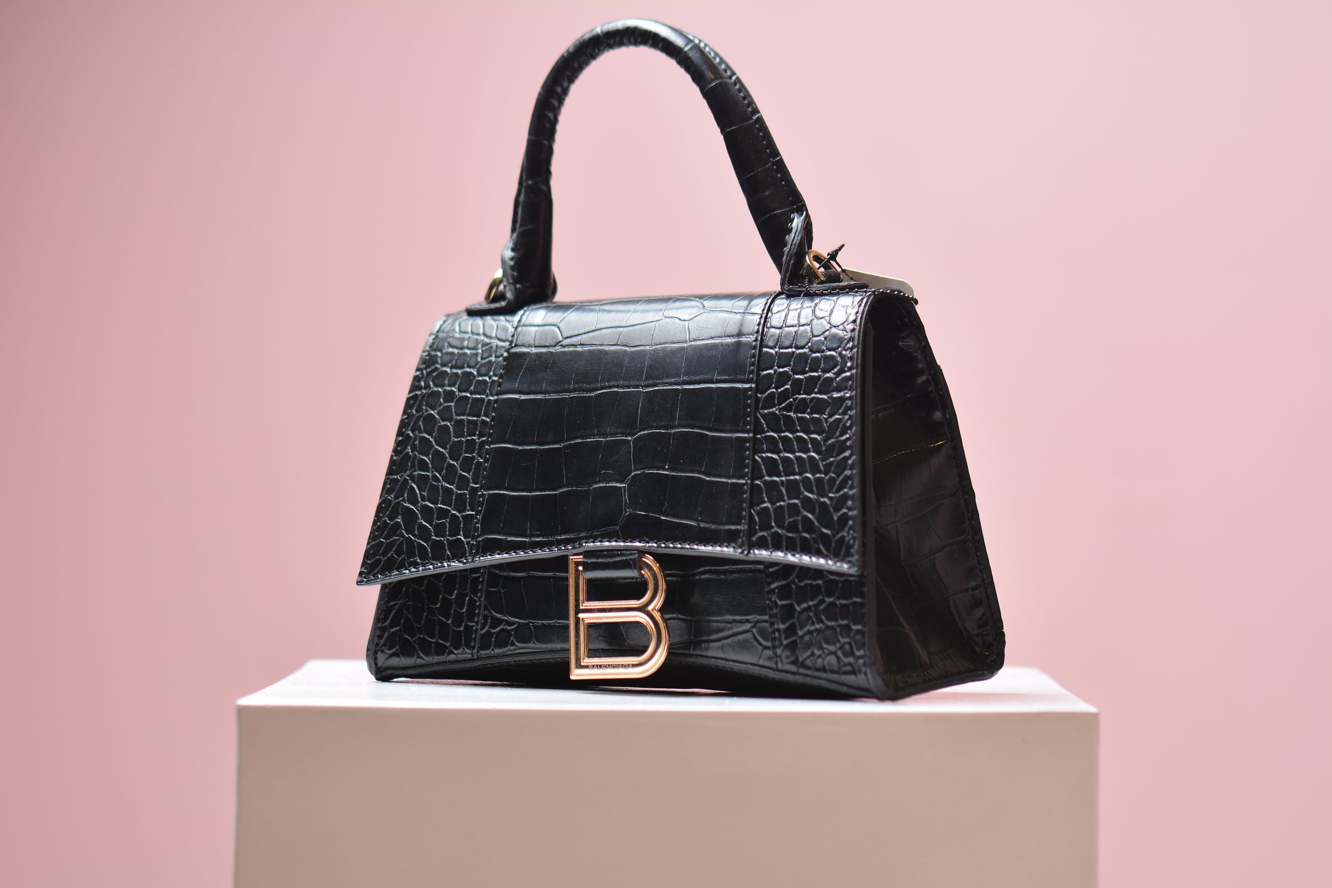 Close-up of a structured canvas luxury handbag with subtle geometric pattern