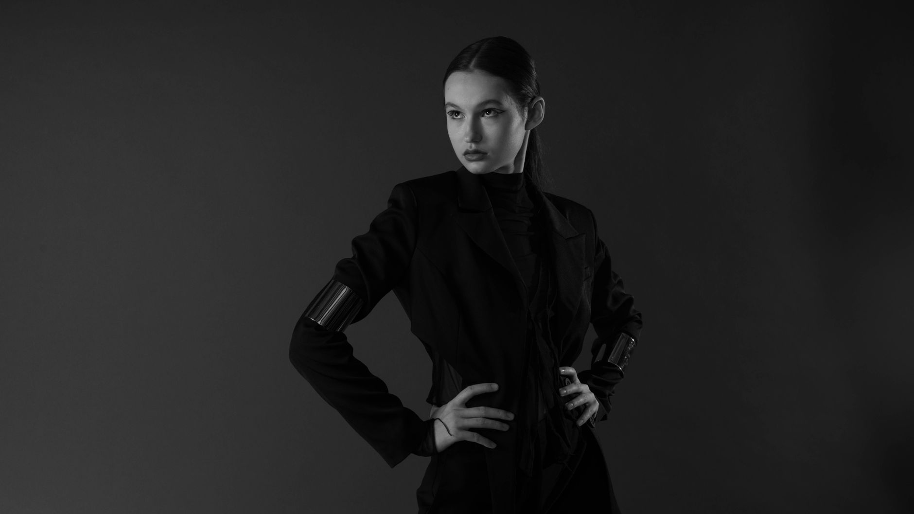 High-fashion editorial photograph featuring black outerwear with sculptural silhouette