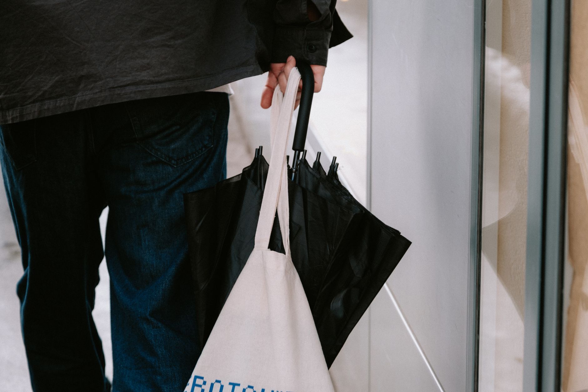 A woman carrying a structured tote bag as part of a polished, minimalist outfit