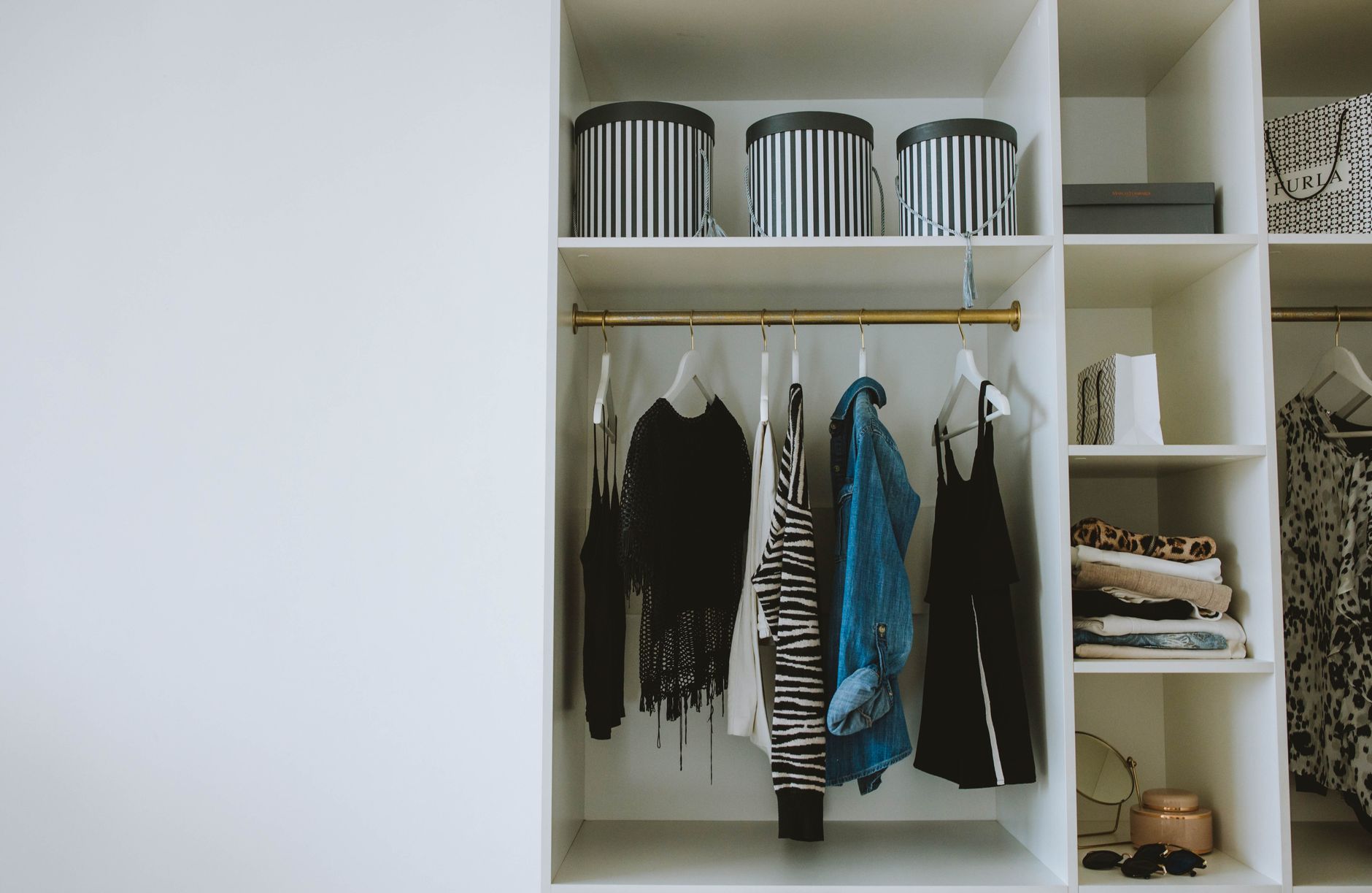 A curated wardrobe of neutral-toned clothing pieces hanging in an organized closet