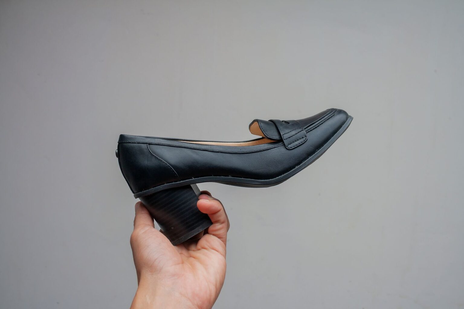 Close-up of woven leather loafers on a wooden surface showing detailed interlaced construction