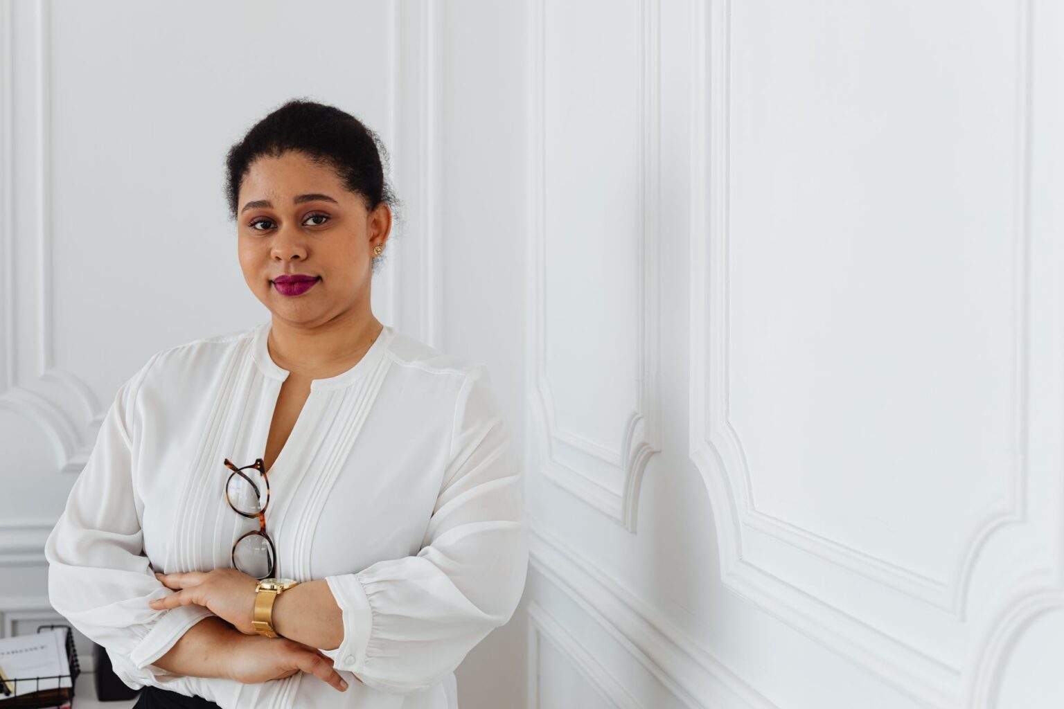 Woman wearing a white gathered shoulder blouse styled with tailored trousers