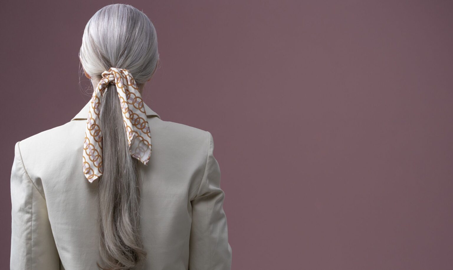 The Slim Scarf Is Quietly Edging Out the Statement Necklace A slim silk scarf tied loosely at the throat over a simple outfit