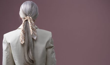 A slim silk scarf tied loosely at the throat over a simple outfit