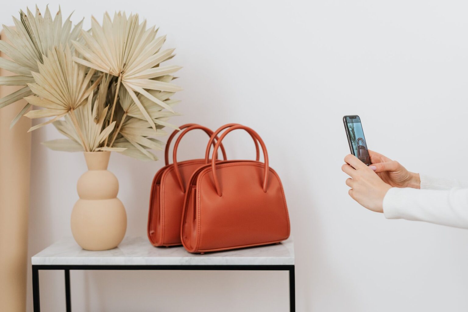 The Trapeze Bag Is Quietly Edging Out the Structured Top Handle A trapeze-shaped leather handbag with a triangular silhouette resting on a neutral surface