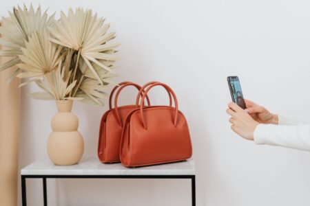A trapeze-shaped leather handbag with a triangular silhouette resting on a neutral surface
