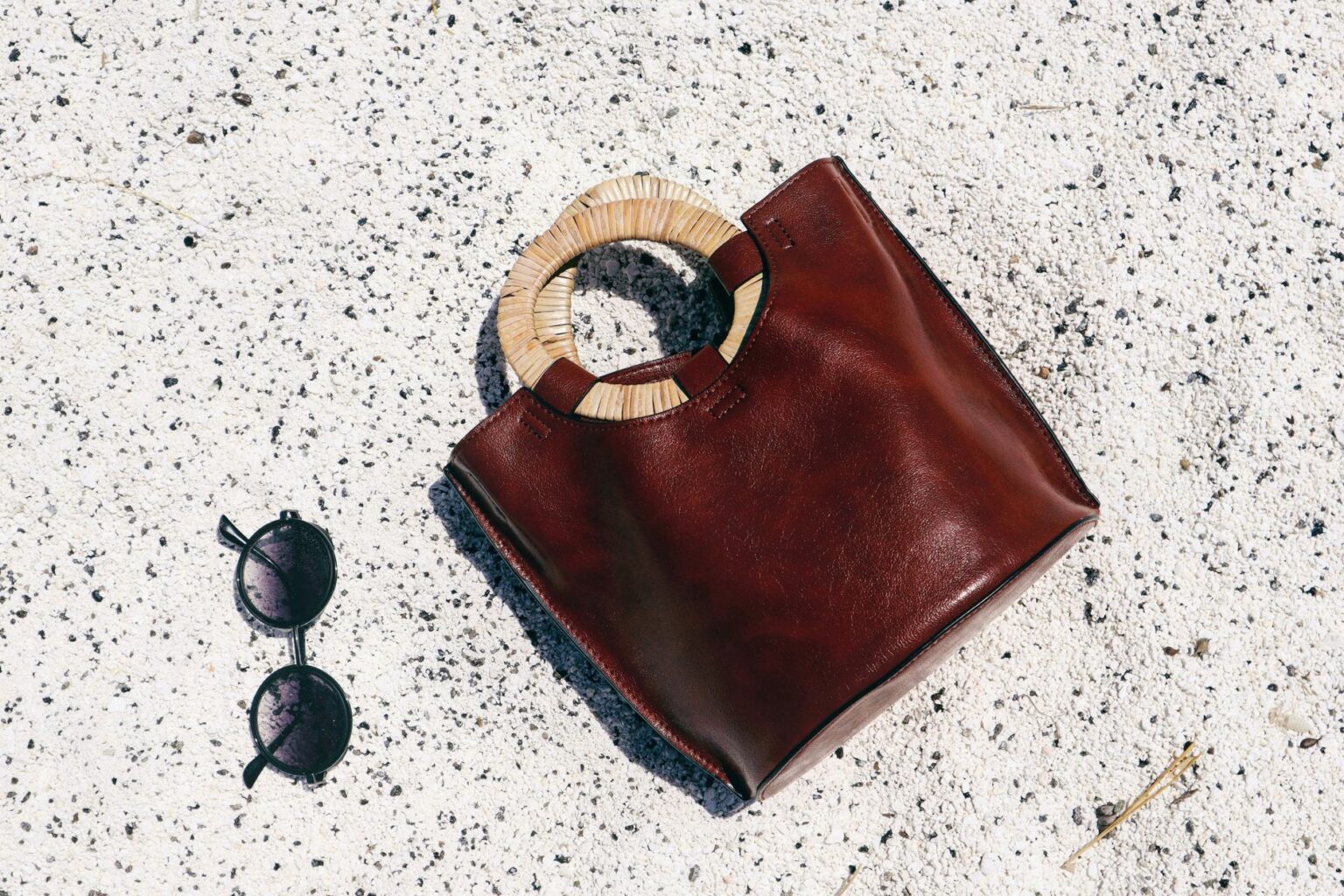 The Raffia Clutch Is Quietly Edging Out the Evening Minaudière A woven raffia clutch bag on a neutral surface, showing natural fiber texture and detail