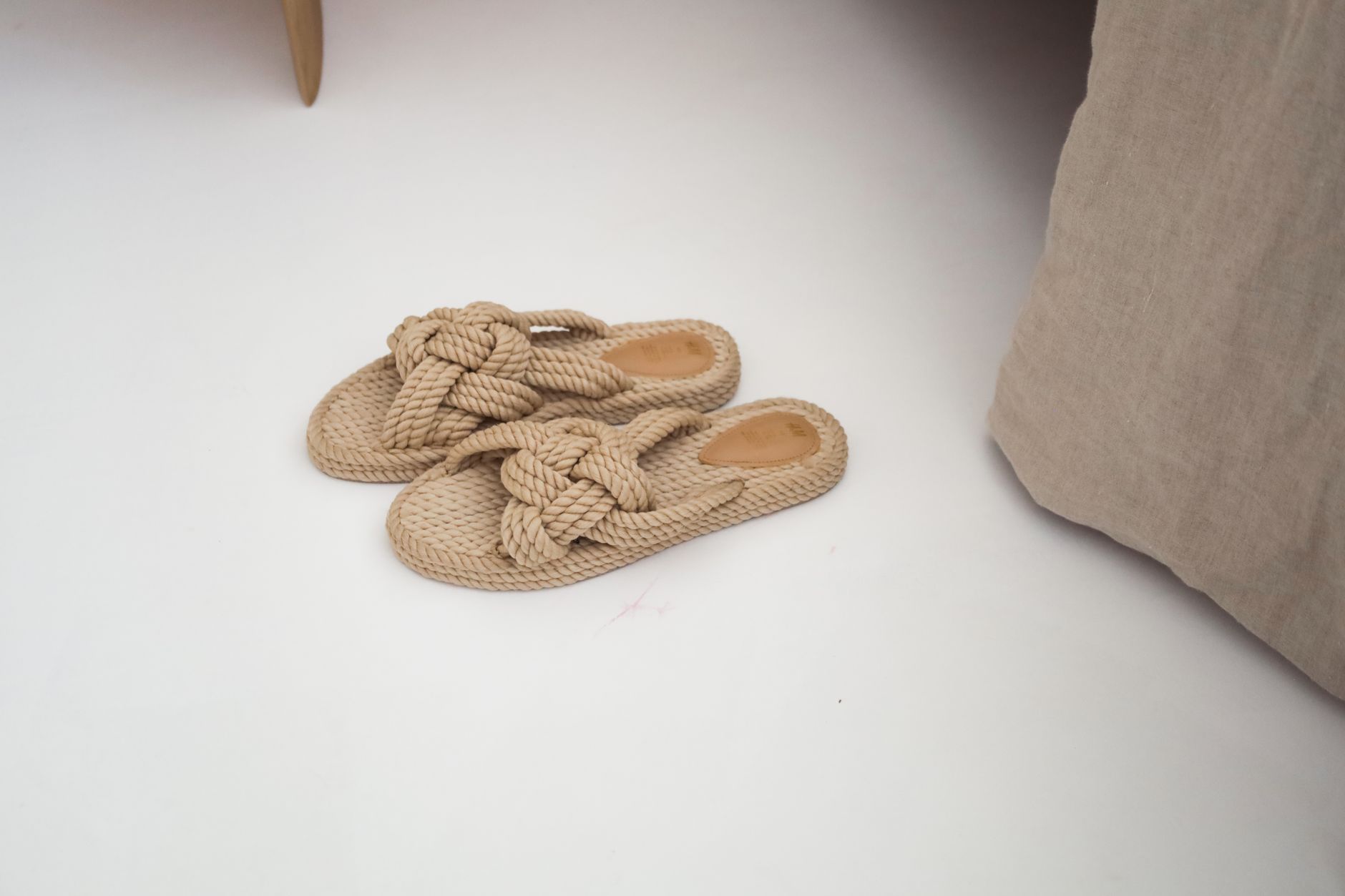 Close-up of woven raffia flat sandals on a light surface