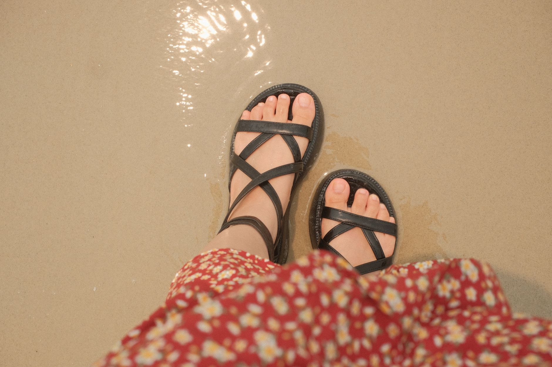 Minimal flat leather sandals on a light background, representing summer footwear trends
