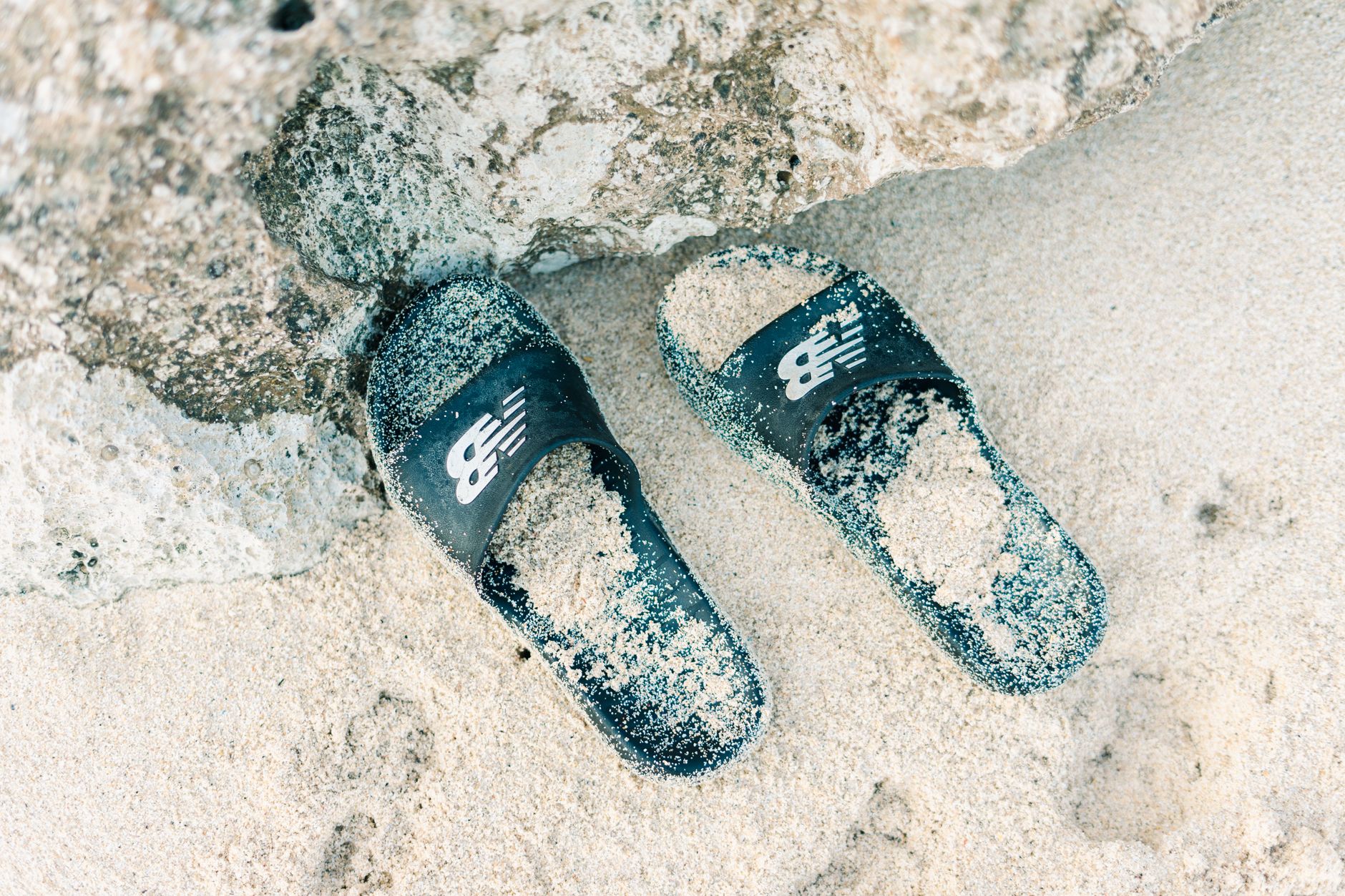 A pair of minimalist leather slide sandals on a neutral background