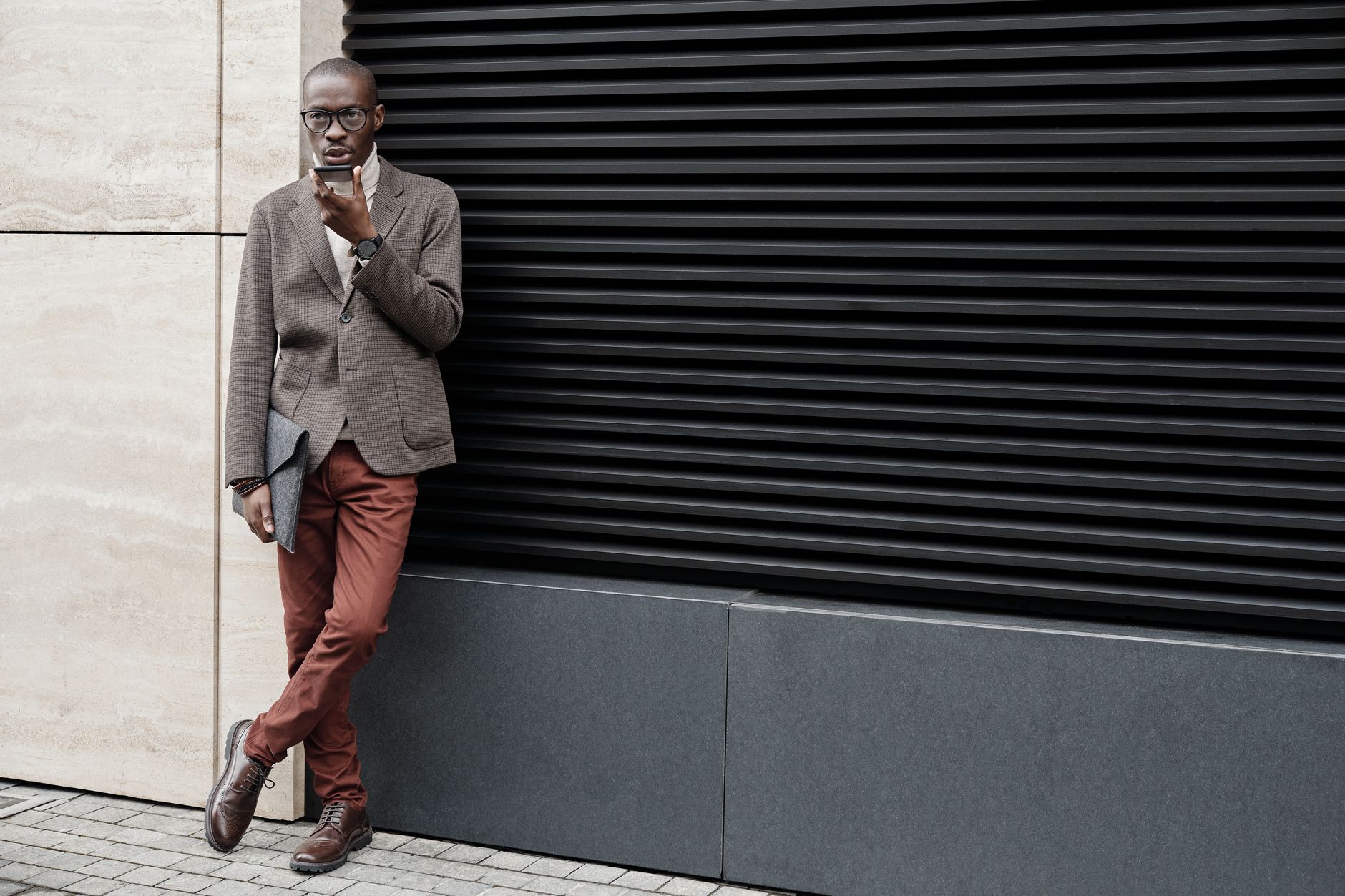 A person wearing a collared knit top with tailored trousers in a minimal setting