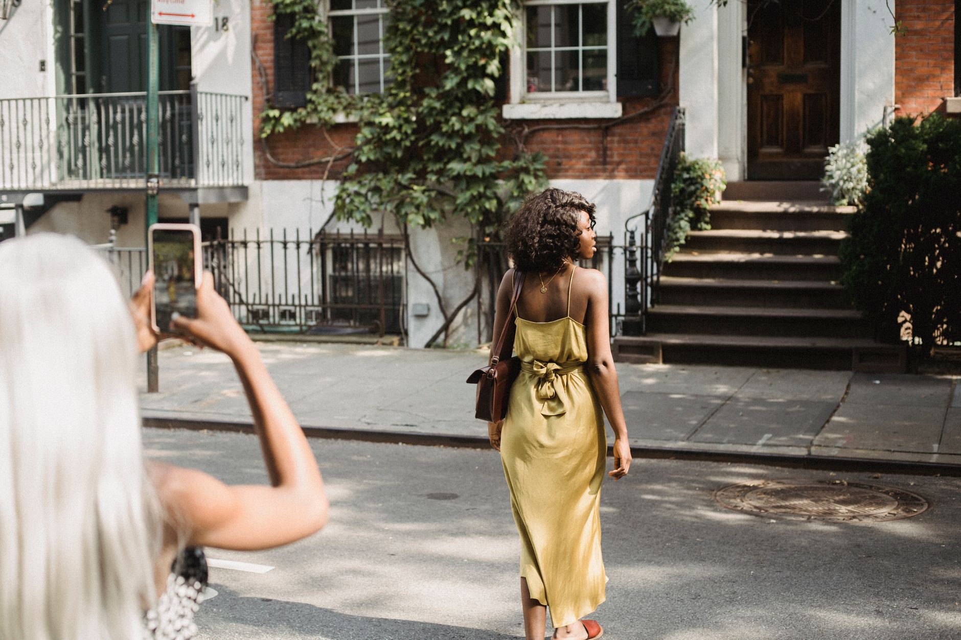 Woman wearing minimal flat sandals with a flowing summer dress on a city street