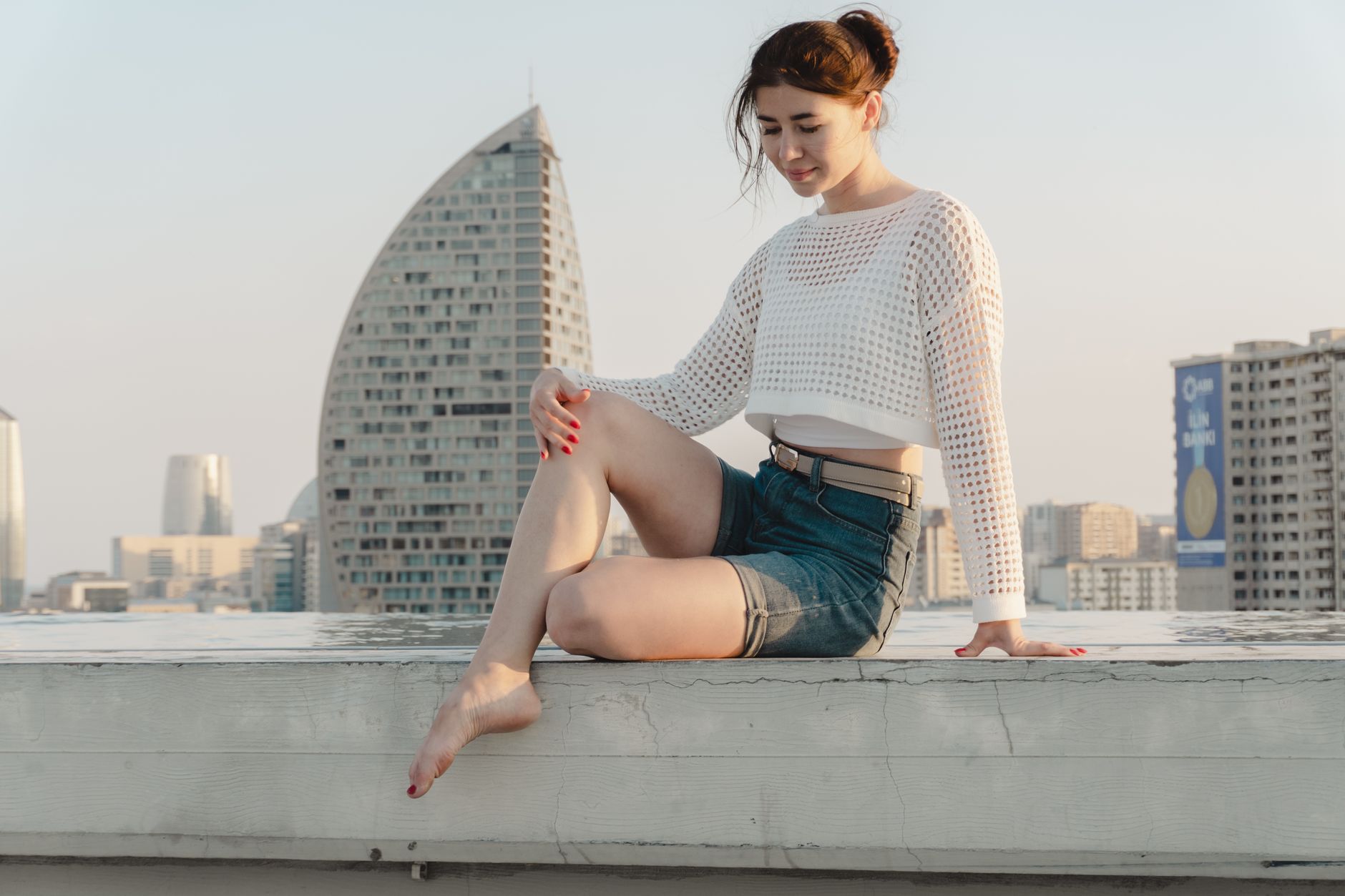 Woman wearing a white cami top with tailored trousers in a casual summer setting