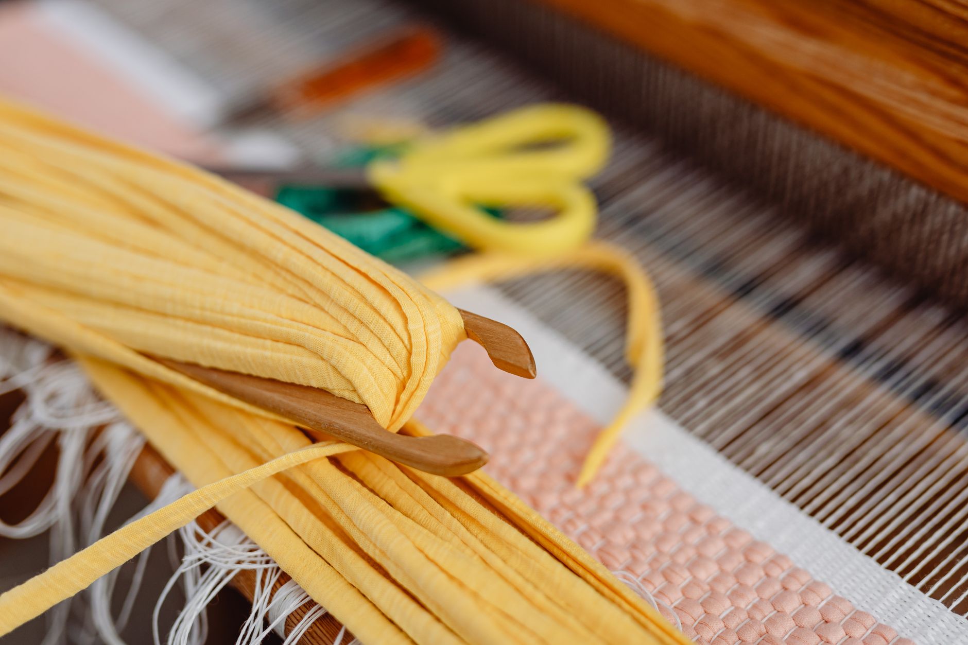 Hands weaving natural raffia fiber into a textured pattern