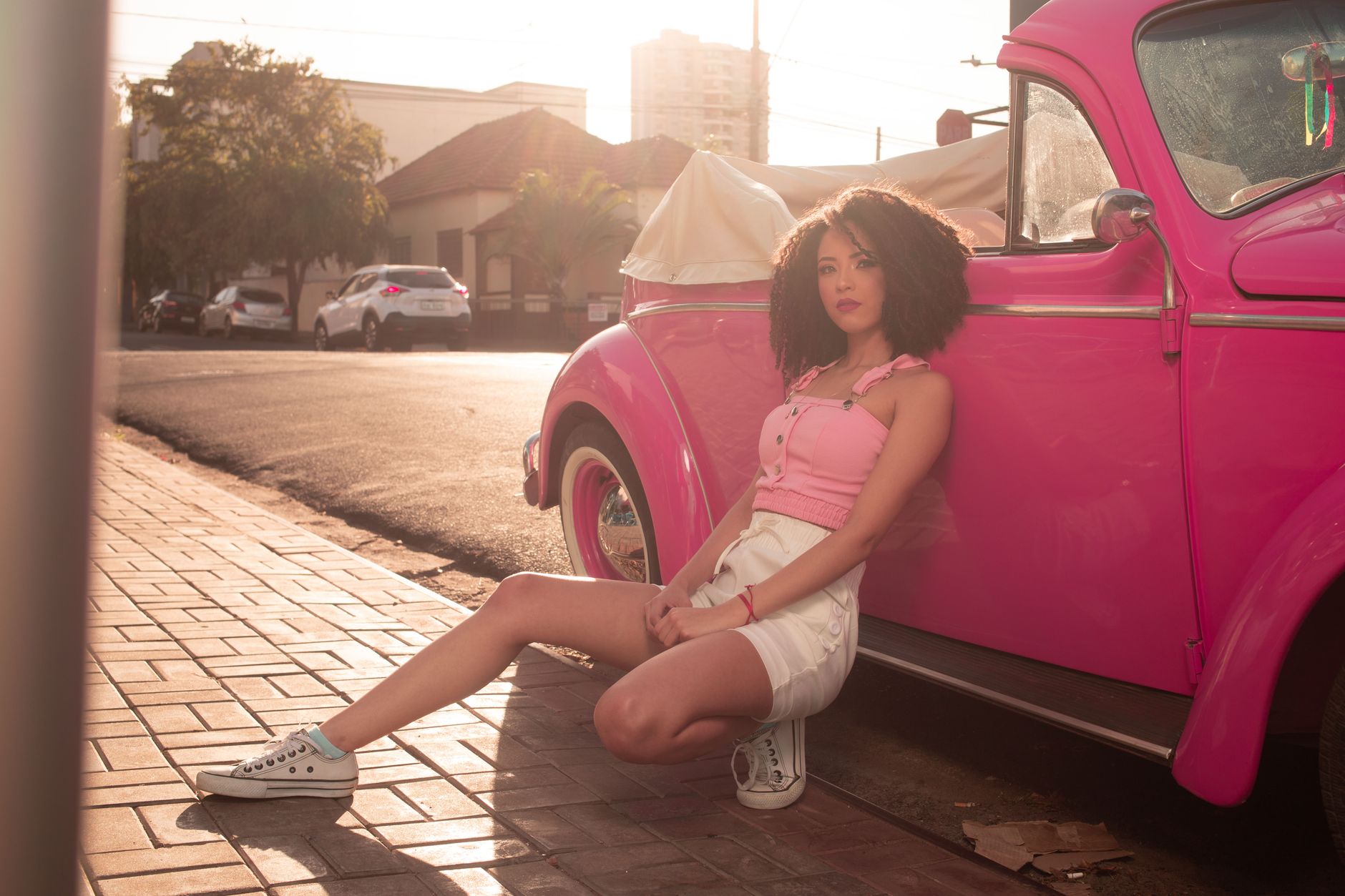 Woman wearing white embroidered shorts with a simple top and flat sandals in a bright outdoor setting